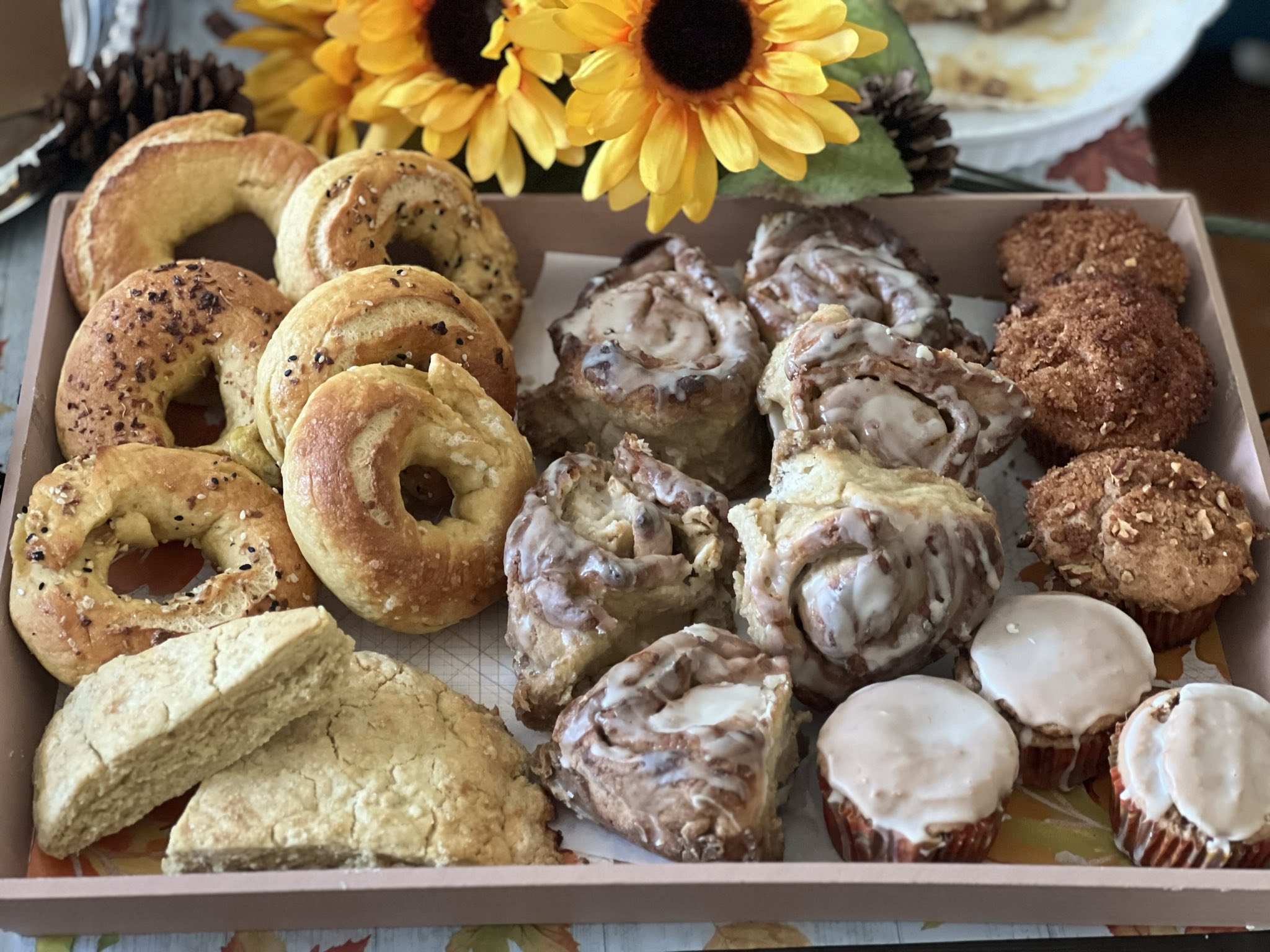 Photo depicts a brunch box that contains bagels, scones, cinnamon rolls, glazed coffee cake muffins, and streusel topped coffee cake muffins.